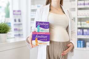 Schwangere Frau in der Apotheke präsentiert Produkte für Schwangerschaft, Stillzeit sowie Baby- und Kindergesundheit.