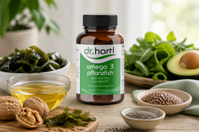 Packung „Dr. Hartl Omega 3 pflanzlich“ mit Algenöl, umgeben von natürlichen Omega-3-Quellen wie Avocado, Lein­samen, Chiasamen, Walnüssen und Algen.