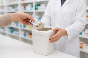 Person gibt alte Medikamente in einen Sammelbehälter in der Rotunden Apotheke – Symbolbild für die fachgerechte Entsorgung von Altmedikamenten.