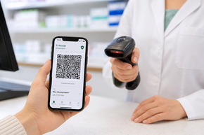 Kundin zeigt ein E-Rezept auf dem Smartphone in der Apotheke, während der QR-Code mit einem Scanner eingelesen wird.