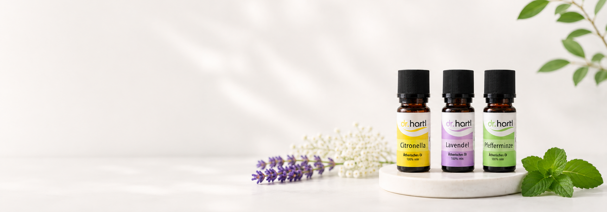 Dr. Hartl ätherische Öle mit Citronella, Lavendel und Pfefferminze neben Kräutern und Pflanzen – Symbolbild für Naturprodukte